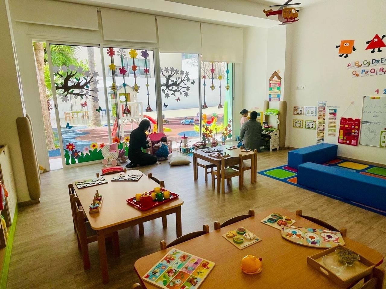 Deux enfants jouent dans la salle de vie lumineuse de M Garden, ouverte sur le jardin